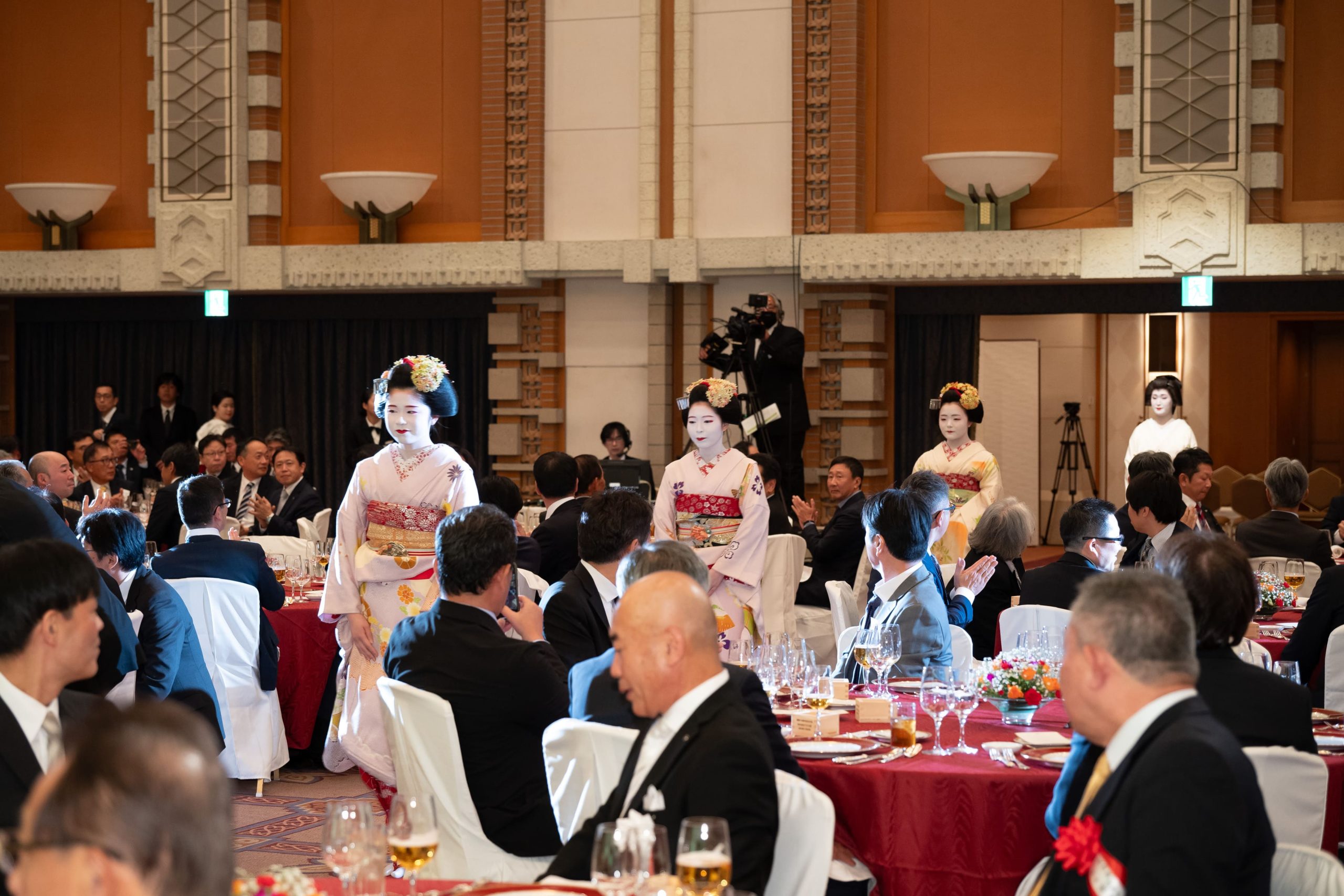 舞妓がテーブル間を歩いて入場する様子